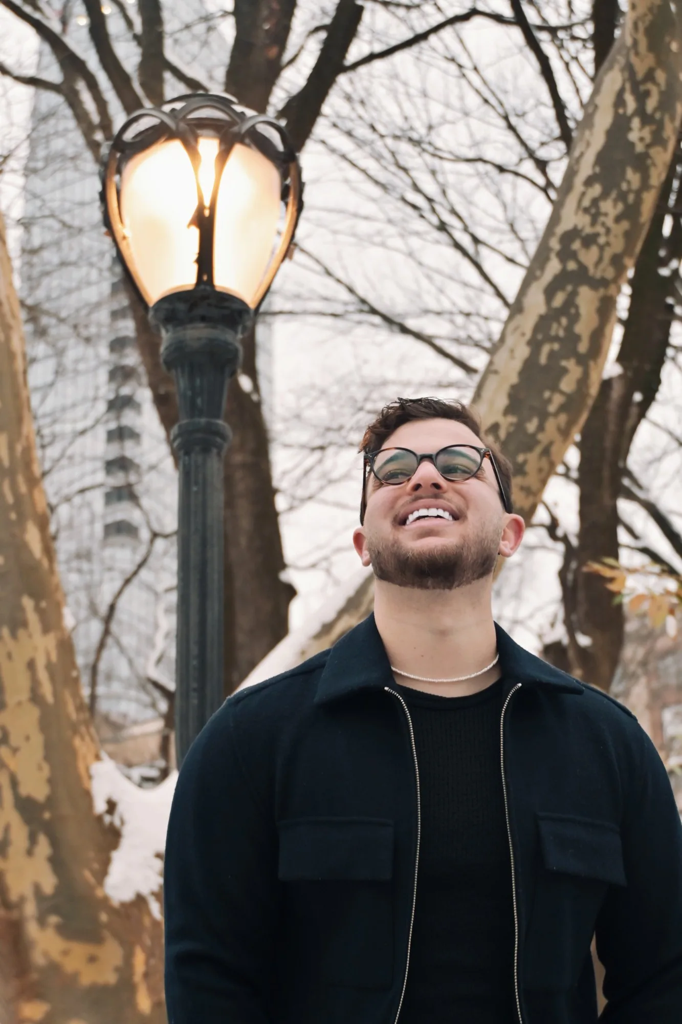 Yuval Gerber smiling in a snowy New York park, beneath a lit Central Park lamppost.
